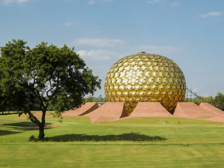 The golden Matrimandir dome at Auroville with a tree in front
