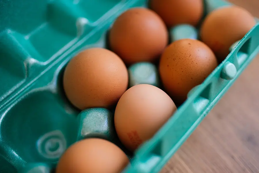 Fresh brown eggs in a carton on a wooden counter