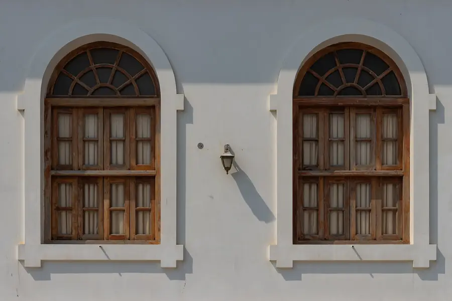 Arched wooden windows on a white heritage wall in Pondicherry's French Quarter